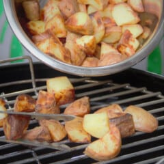 Diced potatoes are being poured onto a grill to cook.