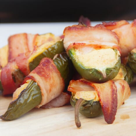 A stack of grilled jalapeño poppers on a chopping board waiting to be eaten.