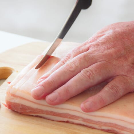 Raw pork belly having thin slices cut into it.
