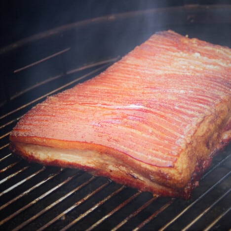 A slab of golden roasted pork belly still on the barbecue.