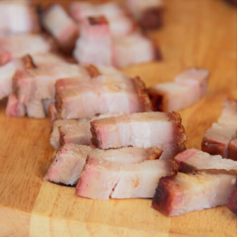 Small cubes of the pork belly on a chopping board.
