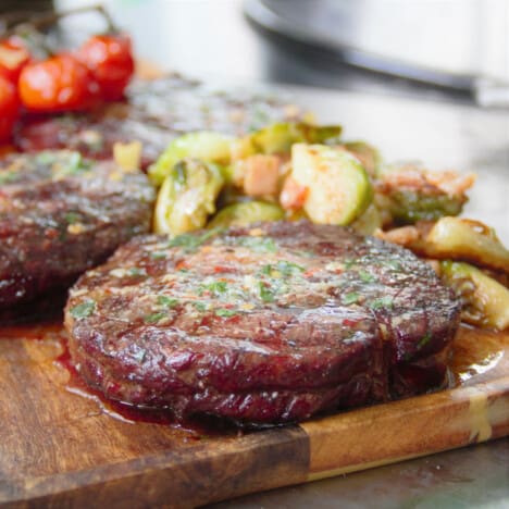 A cooked Scotch steak topped with melted compound butter is served on a wooden chopping board.