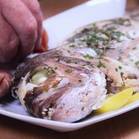 The snapper being arranged on a white platter ready to be served.