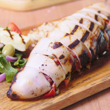 A chorizo-stuffed squid sliced on a chopping board ready to be served.