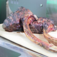 Two fully cooked tomahawk steaks resting on a plastic chopping board after grilling.