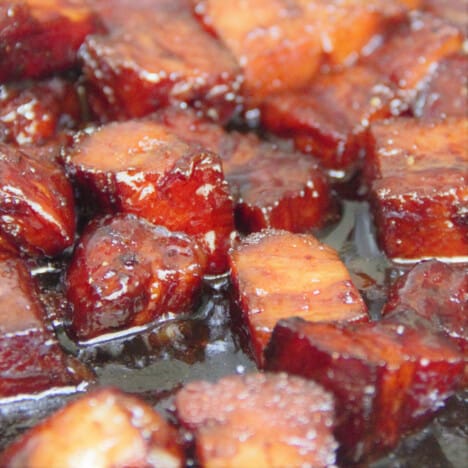 A close up shot of Chinese braised pork belly cubes in a shiny sauce.