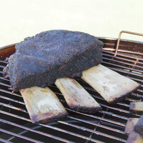 A rack of beef rubs is sitting on a smoker rack almost cooked.