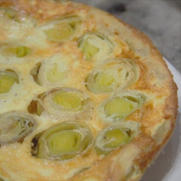 A whole leek tart tartin, with rounds of leeks sitting in an egg custard and surrounded by a crust.