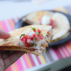 A close up of a wedge of a pulled pork quesadilla with pico de gallo.