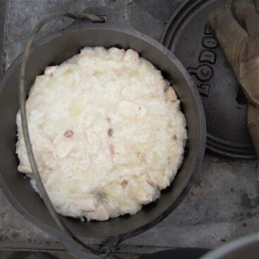 Looking down into a Dutch oven of Campfire Mock Risotto with the lid laid by the side of the pot.