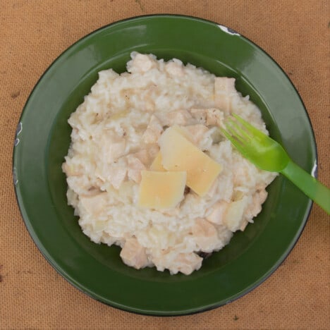 Looking down on to a serving Campfire Mock Risotto in a shallow green bowl on a wood background.