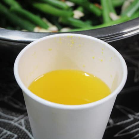 A white paper cup with a mustard dressing.