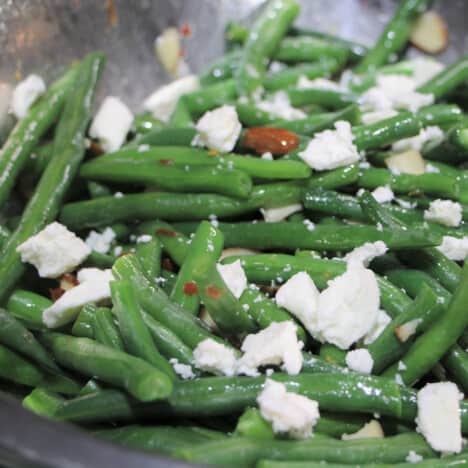 Close up of a green bean salad topped with feta.