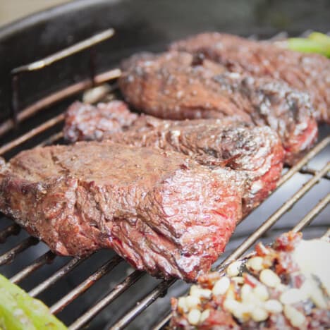 Browned hanger steaks finishing cooking on a grill.