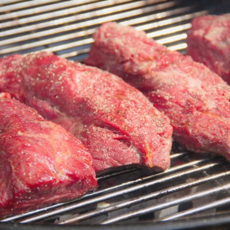 Hanger steaks added to a grill to start the cooking process.