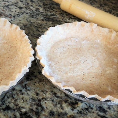 Two pie crusts ready to get be filled with the bacon and onion quiche filling.