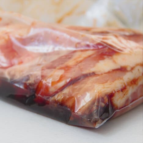 Thinly sliced pork belly is marinating before being grilled.