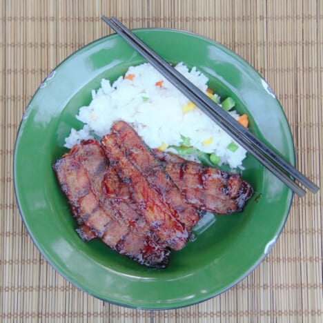 Grilled Asian pork belly is served in a green camping bowl with cilantro rice.