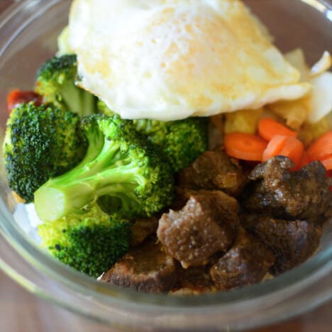 A ready to serve Korean-inspired beef bowl containing broccoli, beef, carrots, cabbage, and topped with a poached egg.