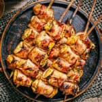 A darky plate with a serving of bacon wrapped turkey skewers