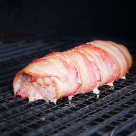 Bacon Wrapped Tenderloin after being smoked, sitting on the grill grates.