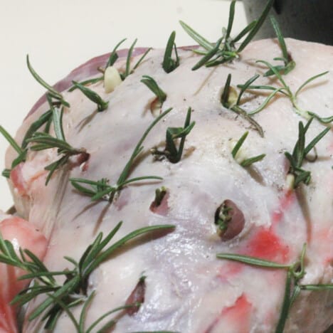 Lamb is infused with garlic and rosemary ready to be added to the Dutch oven to roast.
