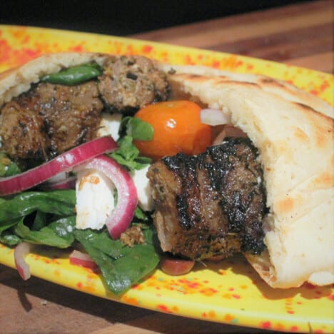 Lamb souvlaki is cooked, stuffed into pita bread with salad, and ready to eat.