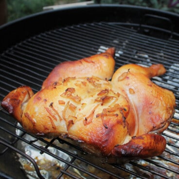 A chicken lays flat on the grill after being marinaded, not being smoked until cooked through.