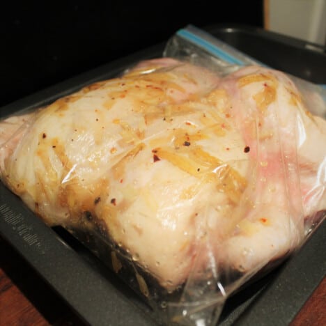 A whole chicken is marinading in a honey and ginger marinade.