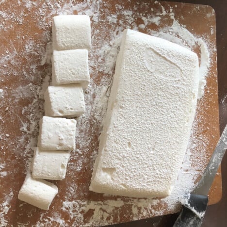 Marshmallow batch on a wooden chopping board with some cut into serving sizes.