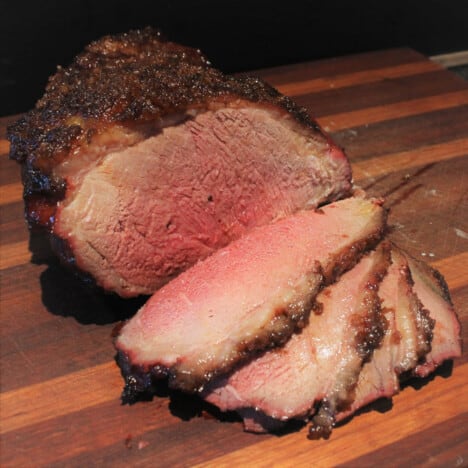 Picanha is sliced showing its soft pink center in contrast to its brown crusty exterior.