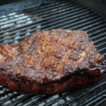 Picanha is cooking in indirect heat on a barbecue.