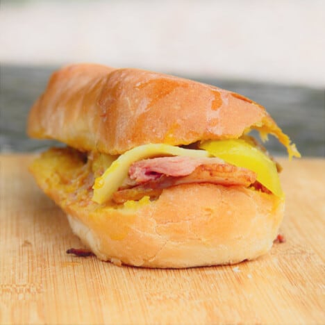 A smoked Cuban Sandwich sits on a chopping board ready to eat.