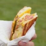 The smoked Cuban sandwich being held in a napkin ready to eat.