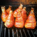 Bacon wrapped chicken drumsticks finishing cooking in the smoker.