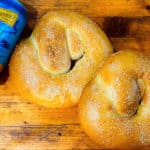 Two beer pretzels sitting on a chopping board ready to eat