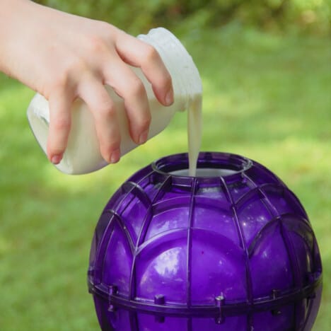 The ice cream mixture being poured from the storage jar into the ice cream maker ball.