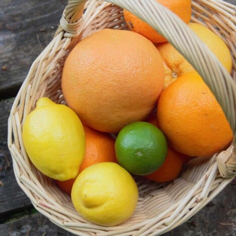 Variety of Citrus fruits sitting in a basket.