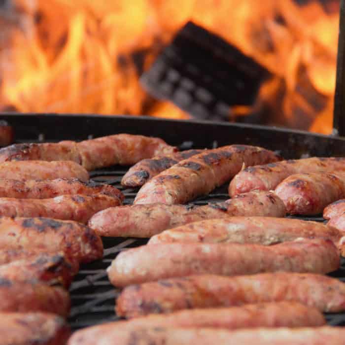 Sausages cooking on a live fire grill