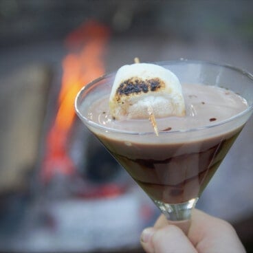A marshmallow on a toothpick tops a chocolate milk smore mocktail.