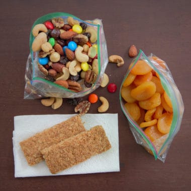 Areal photo of various snacks including dried fruit, trail mix, and muesli bars.