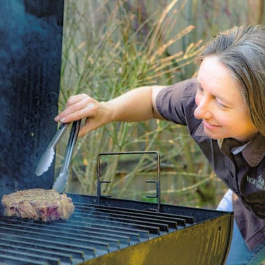 Saffron Hodgson checking the denseness of a steak on the grill