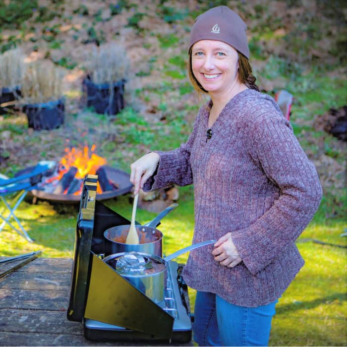 Saffron Hodgson is stirring a saucepan on a camp gas stove