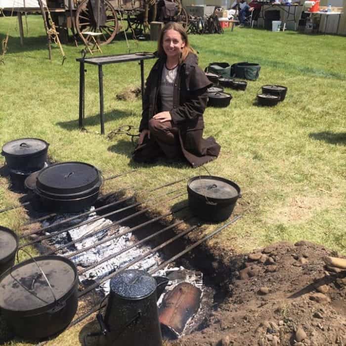Saffron Hodgson sitting next to a trnch fire with multiple cast iron items around her
