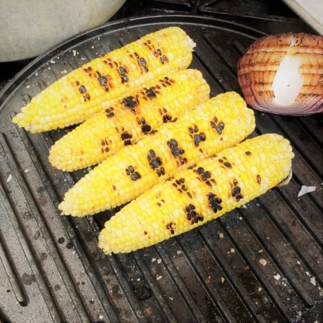 Corn and red onion cooking on the grill.
