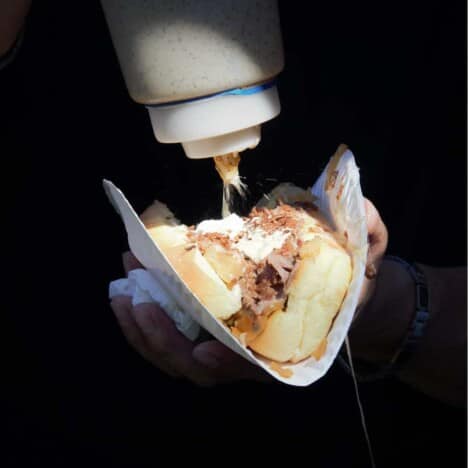 A meat roll with mayo being added