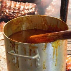 Large pot of sauce with meat in the background