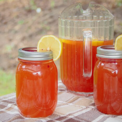 Two servings of the Raspberry Arnold Palmer in jars, with the remaining in a jug in the background.