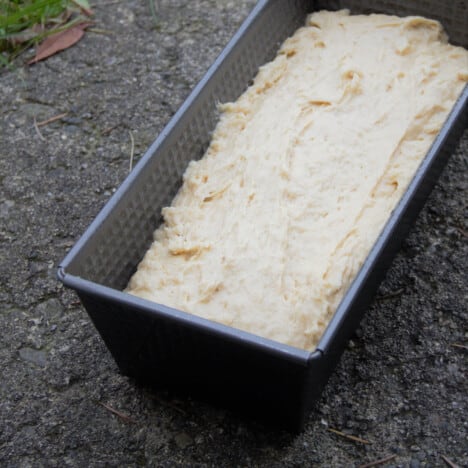 Banana bread batter is in a baking loaf tin.