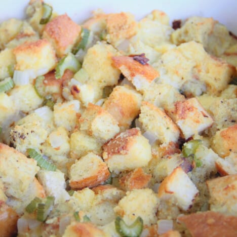 A close up of cooked cornbread stuffing, with golden brown bread cubes.